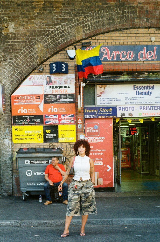 Woman beneath a brick arch and colourful shop signs