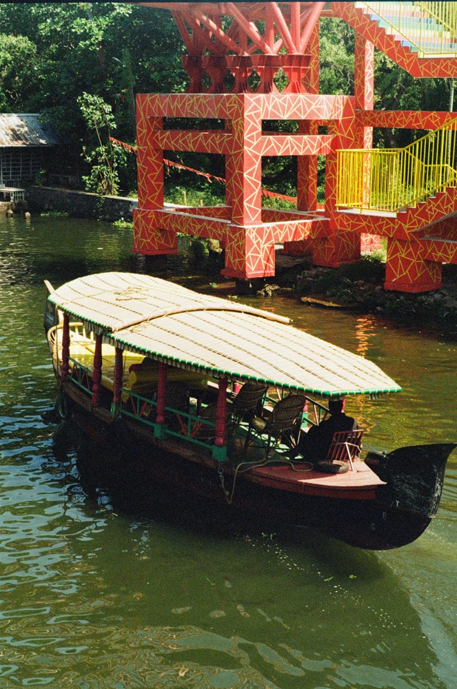 Covered boat beside a red and yellow bridge