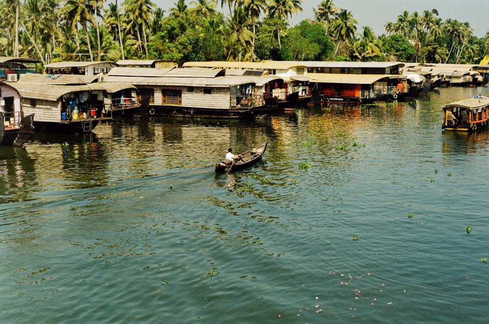 Canoe crossing a canal lined with houseboats