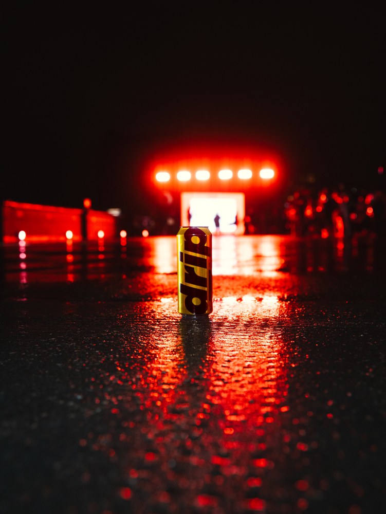 Drip Water can on reflective pavement under red lights